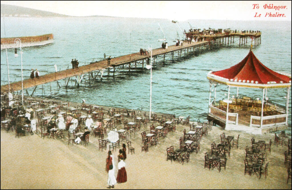 Η παραλία του Νέου Φαλήρου, με την μακρόστενη θαλάσσια εξέδρα, τα διατεταγμένα τραπεζοκαθίσματα και το κιόσκι της μπάντας (επιχρωματισμένο ταχυδρομικό δελτάριο). 