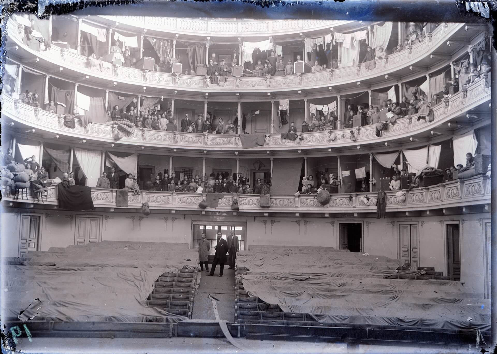 Πρόσφυγες από τη Μικρά Ασία φιλοξενούμενοι προσωρινά στα θεωρεία του Δημοτικού Θεάτρου Αθηνών. (Φωτογραφικό Αρχείο ΕΛΙΑ-ΜΙΕΤ)