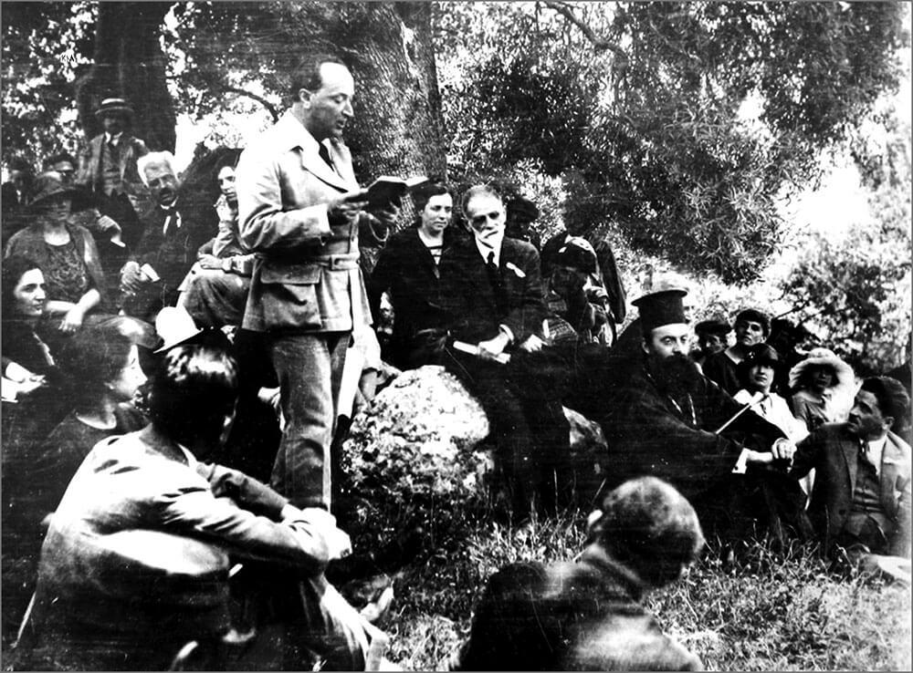 Ο Σικελιανός στη Μαδουρή Λευκάδας, διαβάζει ποίημα του Βαλαωρίτη, μπροστά στον Παλαμά, στον μετέπειτα Πατριάρχη Αθηναγόρα, στην Κλεαρέτη Δίπλα-Μαλάμου, κ.ά. (Ιούνιος 1925). Αρχείο Κ. Μπουρναζάκη