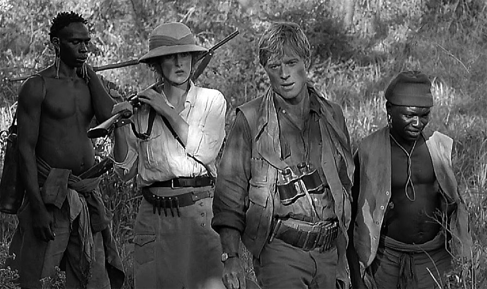 Με ανάλογο όπλο αλλά διαφορετικό καπέλο, η (κινηματογραφική) Κάρεν Μπλίξεν συνοδεύει στη ζούγκλα τον ομόλογο του Ντένις Φιντς Χάτον, Ρόμπερτ Ρέντφορντ. 