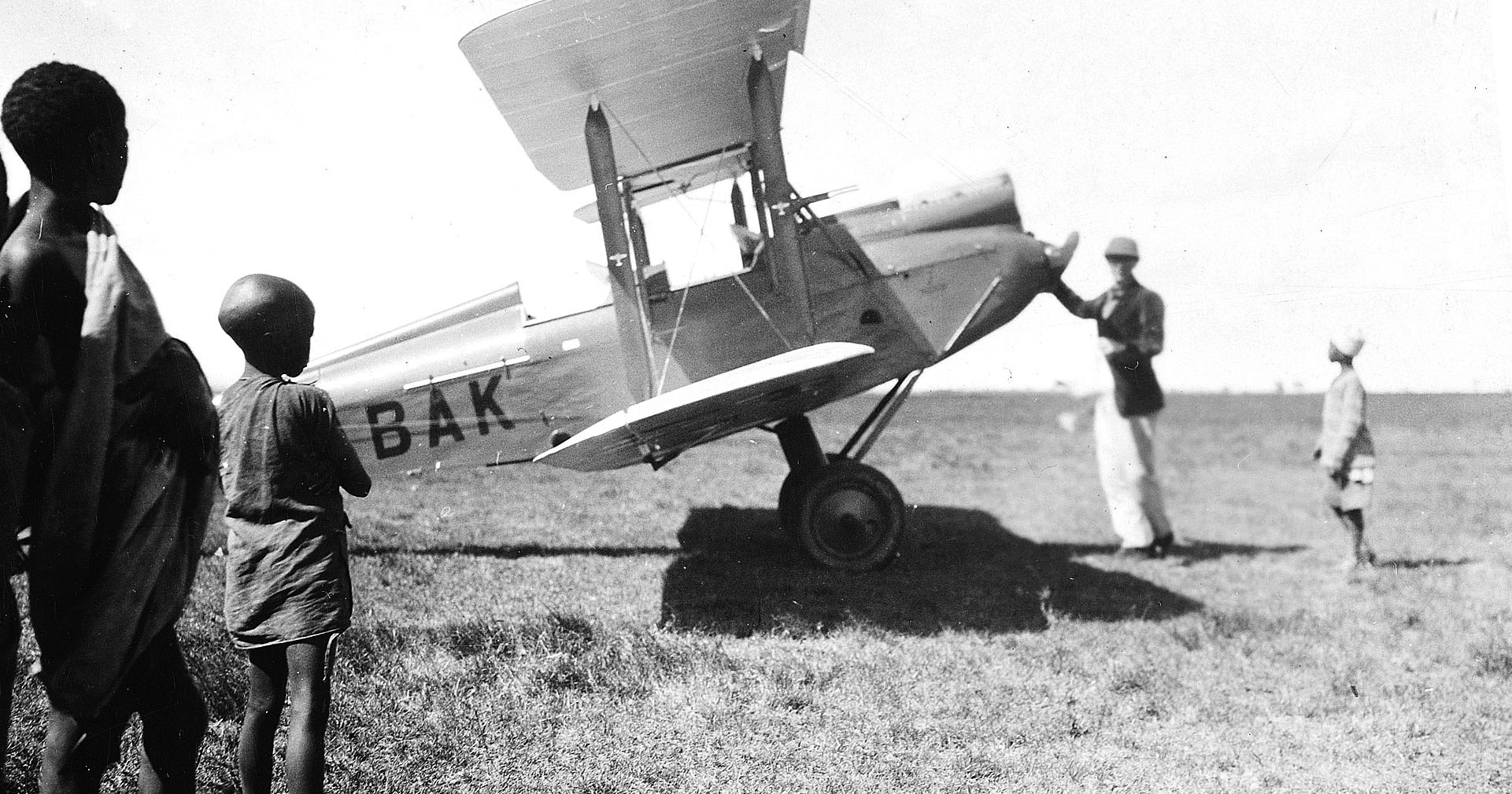 Το διπτέρυγο αεροπλάνο που οδηγούσε ο Ντένις Φιντς Χάτον - και βρήκε το θάνατο με αυτό. Στη φωτογραφία διακρίνεται μπροστά από τον έλικα, πλαισιωμένος μικρούς Κενιάτες. 